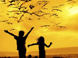 Children dancing under a peaceful sky with seagulls
